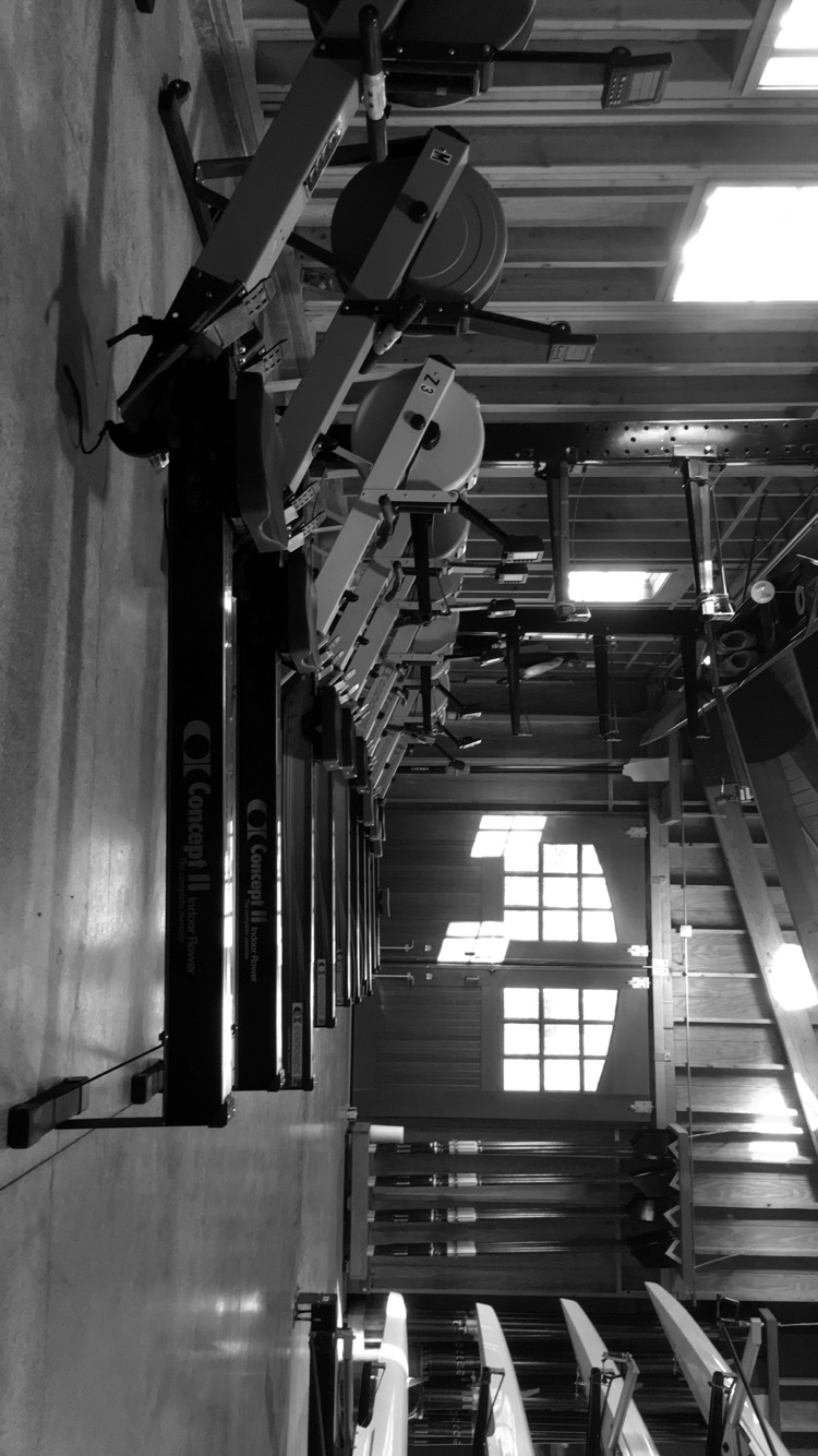 A black and white photo of rowing machines in the RIT boathouse